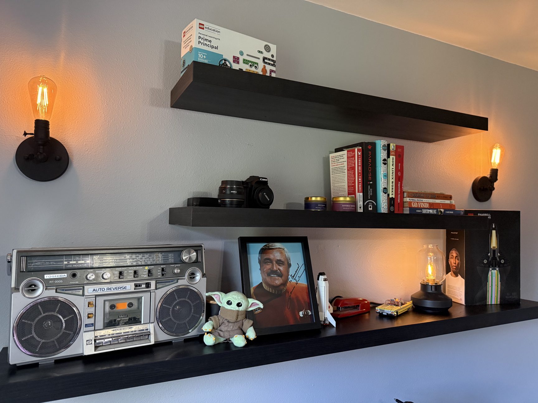 Three IKEA LACK shelves mounted on the wall behind my desk, styled with books, plants, and small objects.